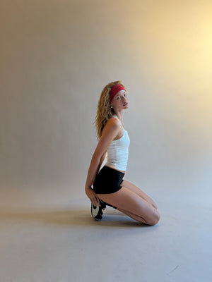 Person in a white tank top and black shorts posing on a light gray background |M1