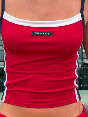 A close-up of a person wearing a red athletic tank top with white trim and navy straps. A small black chest label reads 'DB SPORT'.
|M2