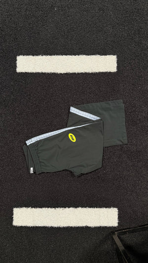Black track pants with a logo on a black textured surface