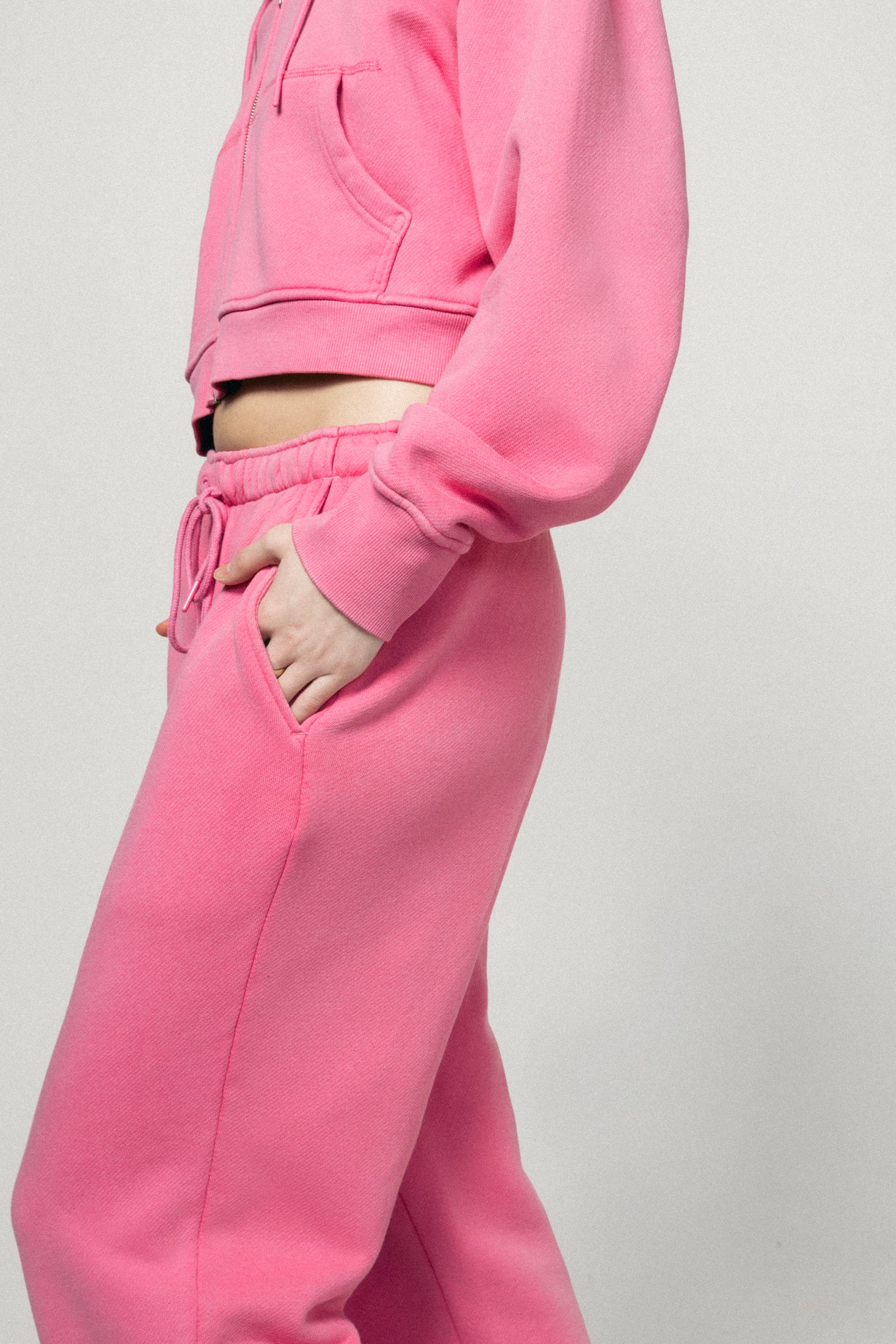 Wearing Dairy Boy’s Milk Bottle Sweatpant in Strawberry Milk, a person stands casually with one hand in their pocket, showing off a comfortable and stylish look against a plain light background.