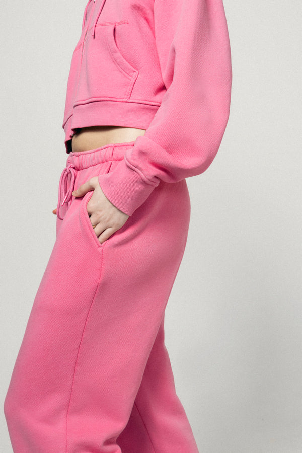 Wearing Dairy Boy’s Milk Bottle Sweatpant in Strawberry Milk, a person stands casually with one hand in their pocket, showing off a comfortable and stylish look against a plain light background.