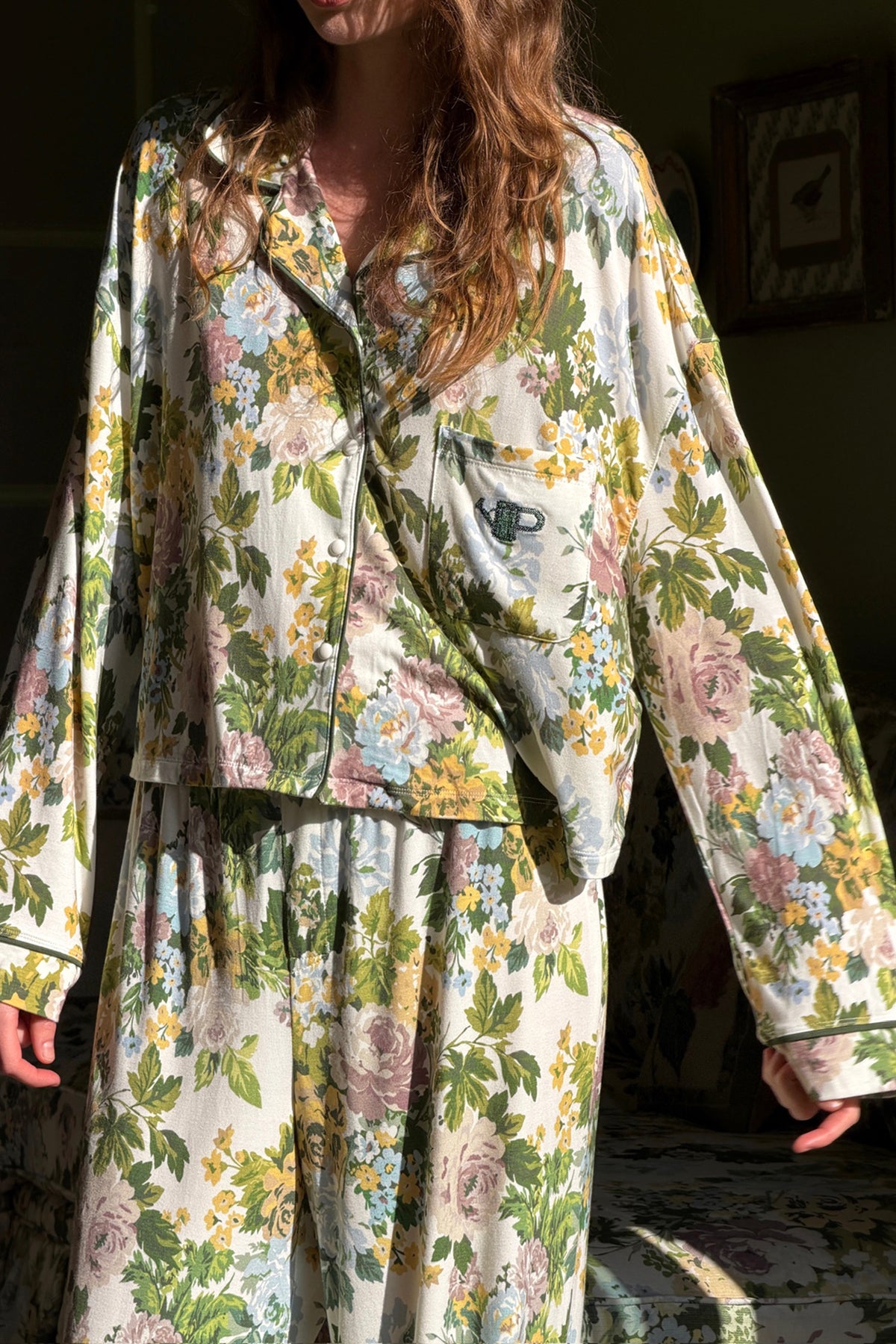 Floral pajama set on a model, a long-sleeve collared shirt with buttons and chest pocket plus matching pants, in green, yellow and blue. |M3