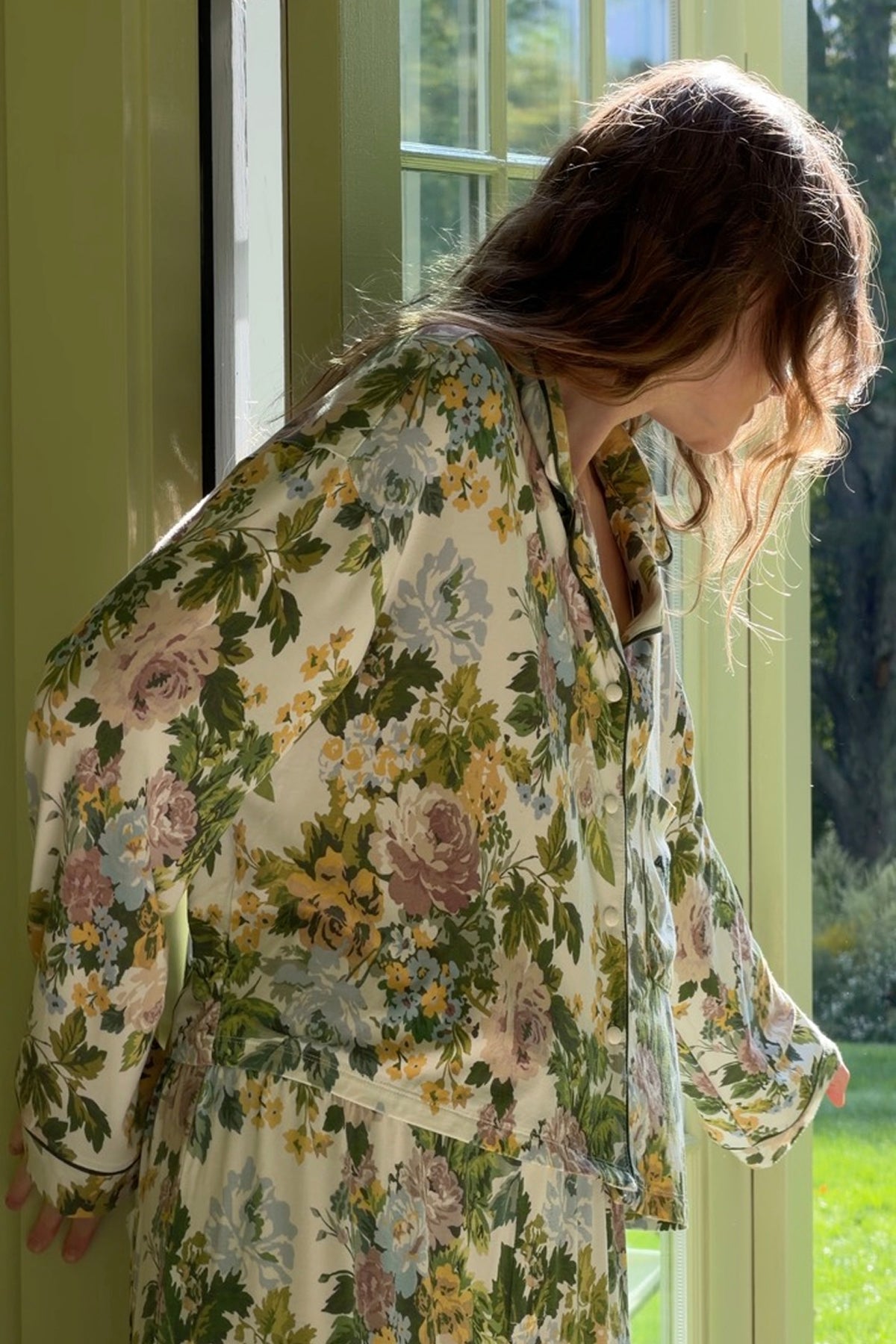 Long-sleeved sleep shirt and matching pants in a cream floral print with green leaves and mauve, blue and yellow blooms, shown on a model.
